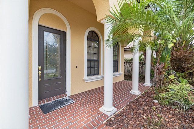 entrance to property featuring stucco siding and covered porch