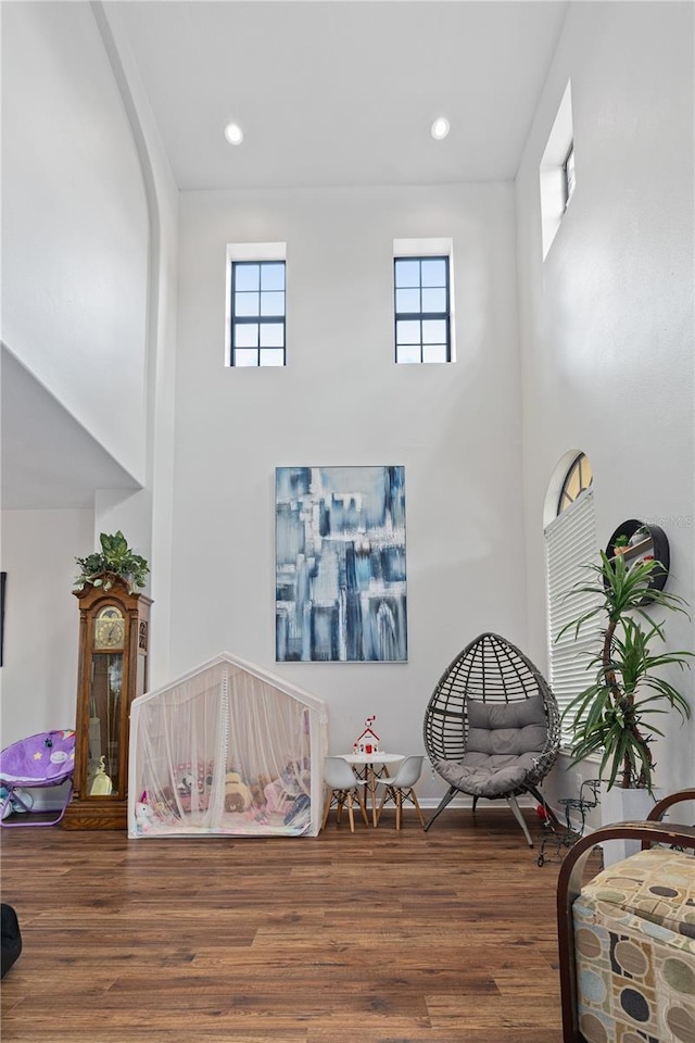 sitting room with recessed lighting, a high ceiling, and wood finished floors