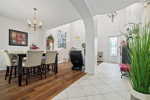 dining room with baseboards, arched walkways, light tile patterned floors, and a chandelier