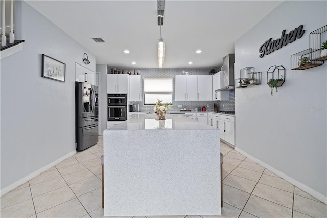 kitchen with dobule oven black, stainless steel fridge, light countertops, wall chimney exhaust hood, and backsplash