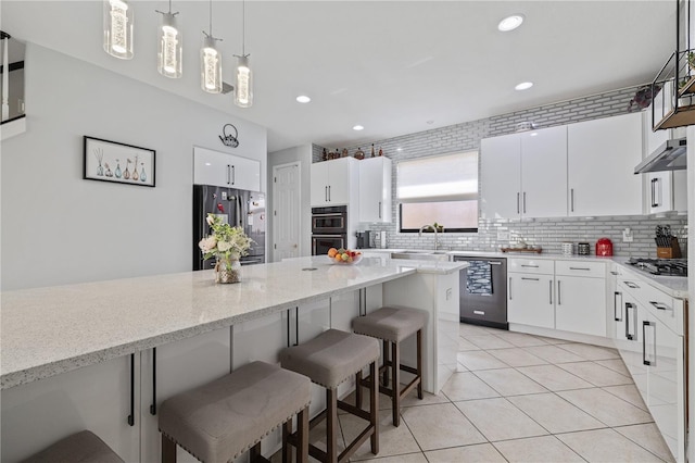 kitchen featuring a breakfast bar, tasteful backsplash, a sink, appliances with stainless steel finishes, and light tile patterned floors