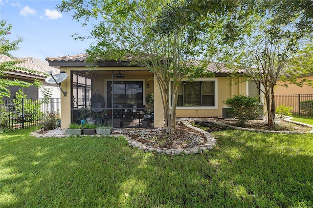back of property featuring fence, stucco siding, a lawn, and a tiled roof