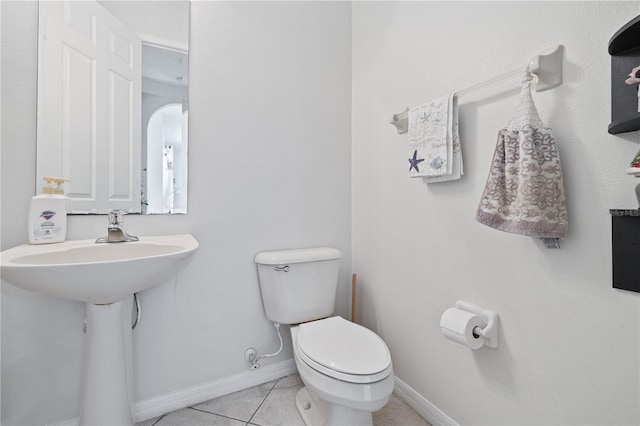 bathroom with toilet, baseboards, and tile patterned flooring