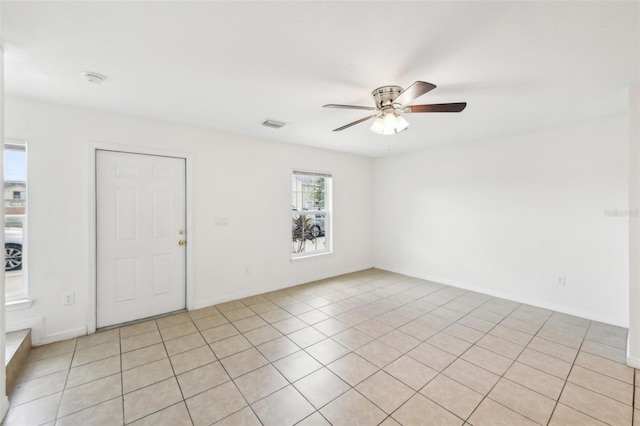 spare room featuring a healthy amount of sunlight, light tile patterned floors, and ceiling fan