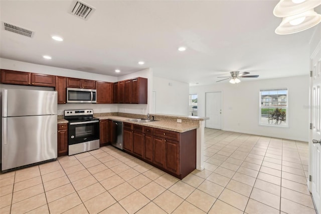 kitchen featuring light tile patterned floors, appliances with stainless steel finishes, light stone countertops, kitchen peninsula, and ceiling fan