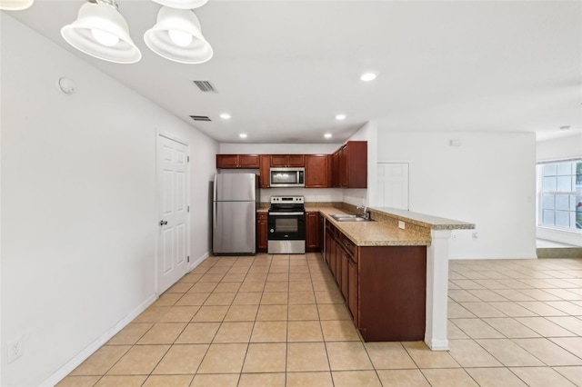 kitchen featuring pendant lighting, kitchen peninsula, sink, appliances with stainless steel finishes, and light tile patterned flooring