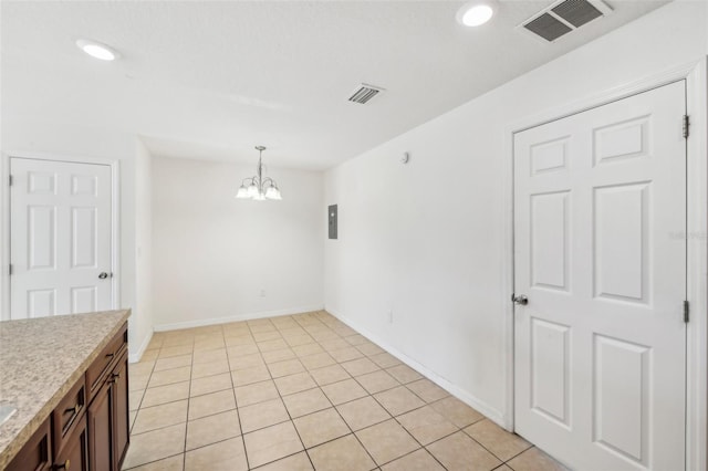 tiled empty room featuring a notable chandelier