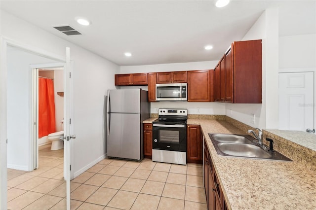 kitchen featuring appliances with stainless steel finishes, light tile patterned floors, and sink