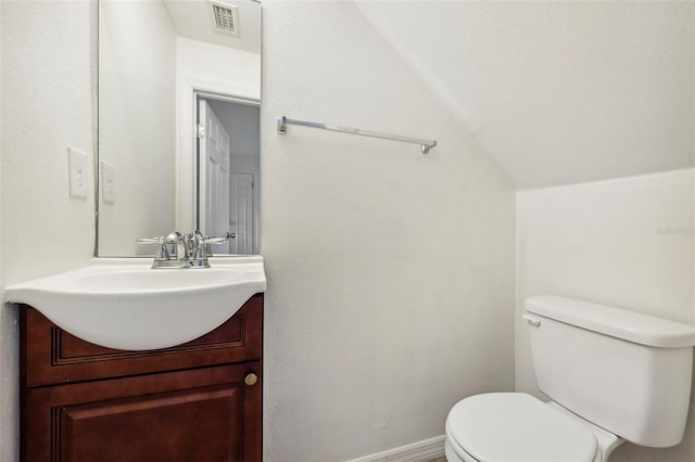 bathroom featuring vanity, toilet, and lofted ceiling