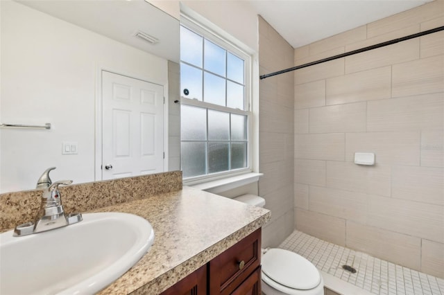 bathroom with tiled shower, toilet, and vanity