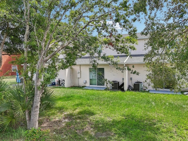 rear view of house with a yard and central AC