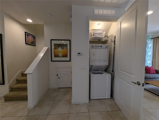 laundry room featuring stacked washer / dryer and light tile patterned flooring