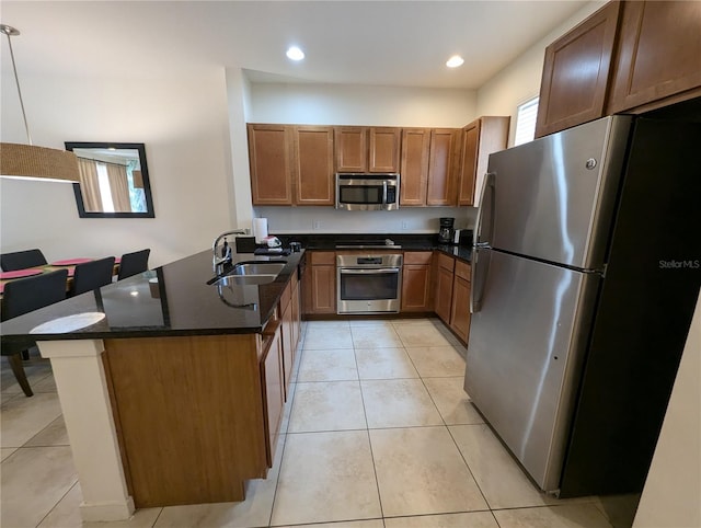 kitchen featuring decorative light fixtures, appliances with stainless steel finishes, kitchen peninsula, sink, and dark stone countertops