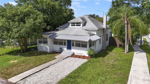 view of front of property featuring entry steps, roof with shingles, a front yard, and fence