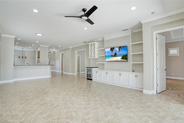 unfurnished living room featuring wine cooler, light tile patterned flooring, built in shelves, ornamental molding, and ceiling fan