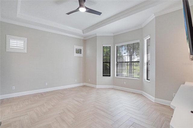 unfurnished bedroom featuring light parquet floors, a tray ceiling, ornamental molding, and ceiling fan