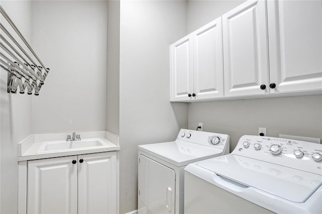 clothes washing area with washer and clothes dryer, sink, and cabinets