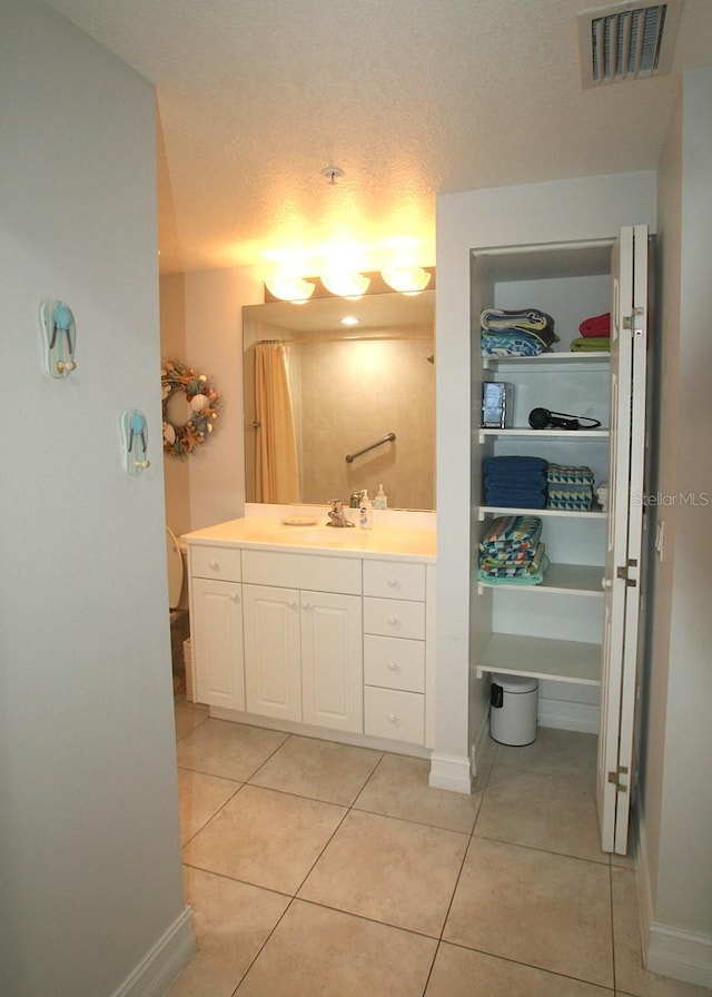 full bathroom featuring visible vents, a textured ceiling, vanity, baseboards, and tile patterned floors