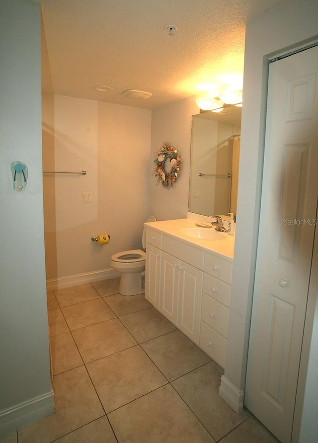 full bathroom featuring toilet, a textured ceiling, vanity, tile patterned flooring, and baseboards