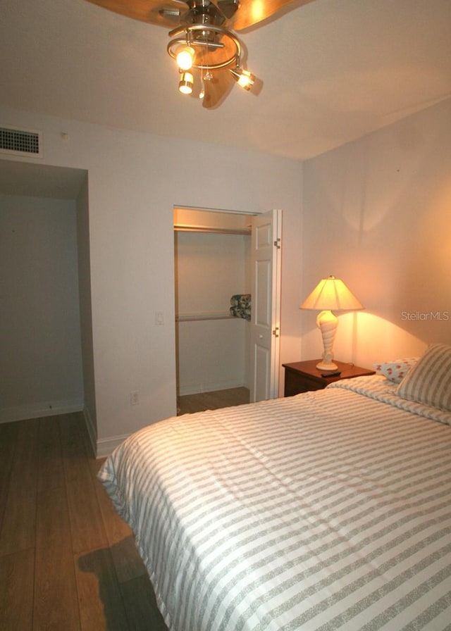 bedroom with a closet, baseboards, visible vents, and hardwood / wood-style floors