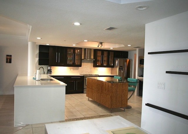 kitchen featuring stainless steel appliances, visible vents, backsplash, a sink, and wall chimney range hood