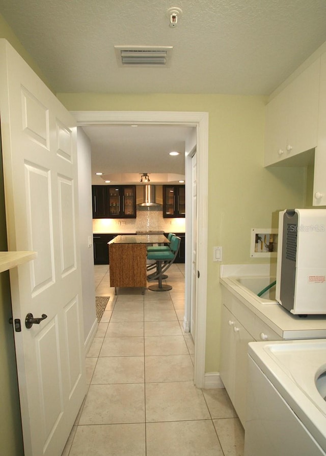 washroom with cabinet space, washer / dryer, baseboards, visible vents, and light tile patterned flooring