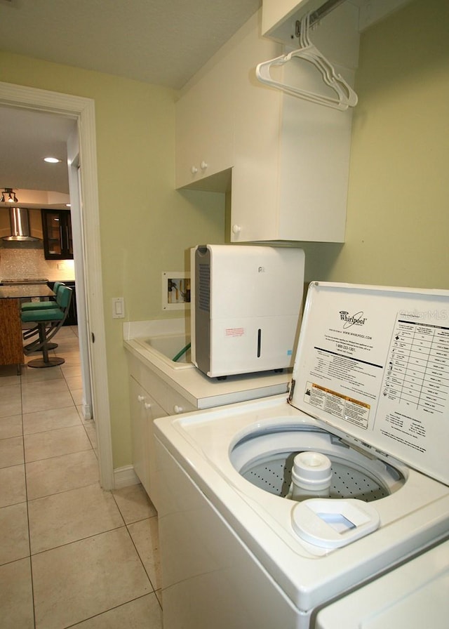 laundry room featuring light tile patterned floors, washing machine and dryer, cabinet space, and baseboards