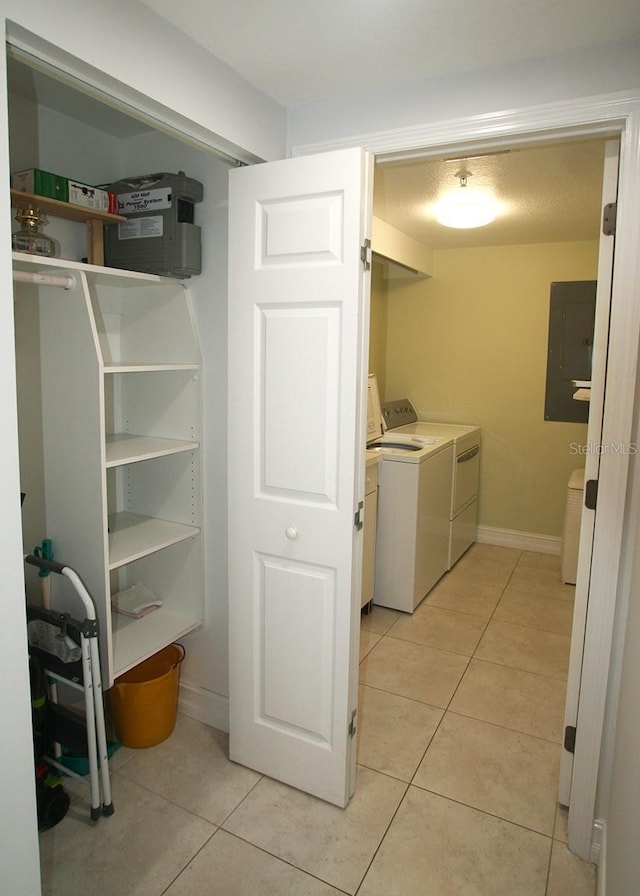 laundry area featuring laundry area, light tile patterned floors, electric panel, baseboards, and washing machine and clothes dryer