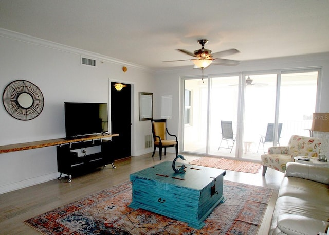 living room featuring a ceiling fan, visible vents, crown molding, and wood finished floors