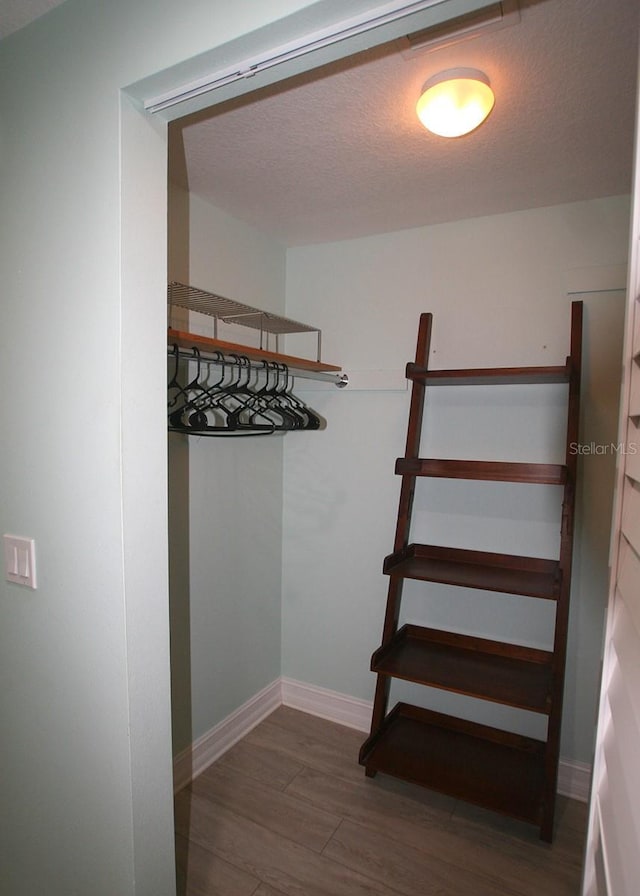 walk in closet with wood finished floors