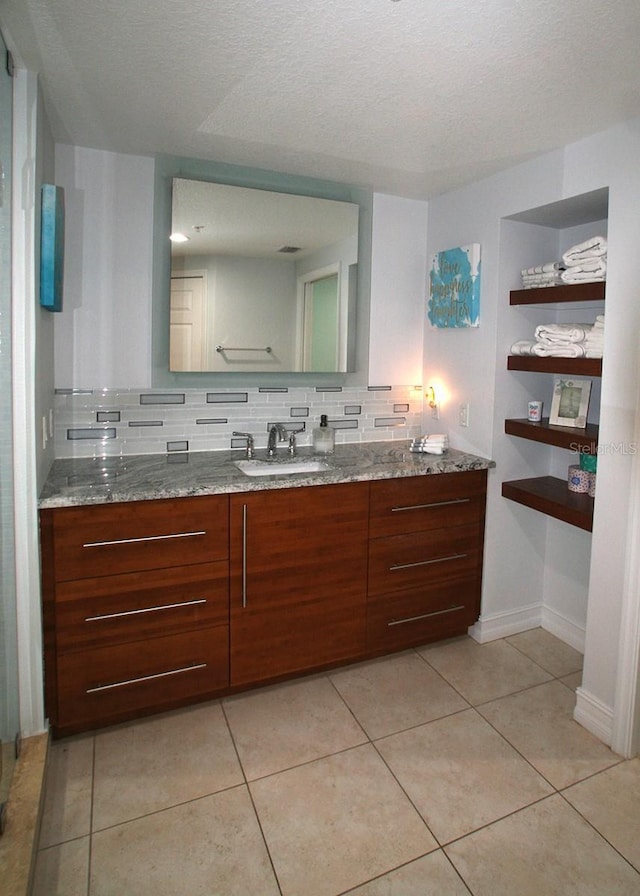 bathroom with baseboards, vanity, decorative backsplash, and tile patterned floors