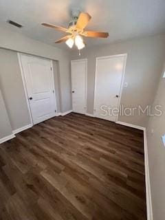 unfurnished bedroom with ceiling fan and dark wood-type flooring