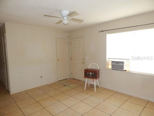 spare room with cooling unit, ceiling fan, and light tile patterned floors