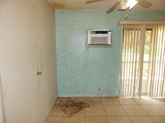 empty room with ceiling fan, light tile patterned floors, and an AC wall unit