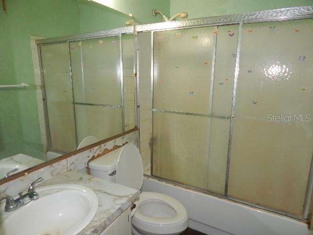 full bathroom with vanity, toilet, and combined bath / shower with glass door