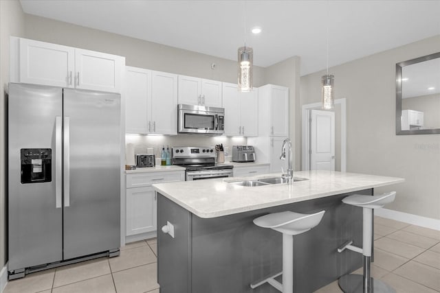 kitchen with pendant lighting, stainless steel appliances, a kitchen island with sink, and sink