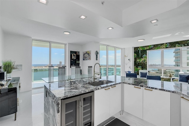 kitchen featuring stone countertops, sink, light tile patterned floors, and white cabinetry