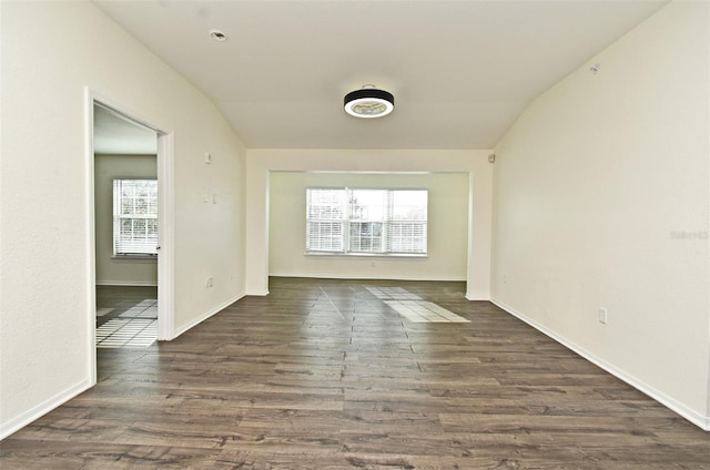 unfurnished room featuring dark hardwood / wood-style flooring, vaulted ceiling, and plenty of natural light