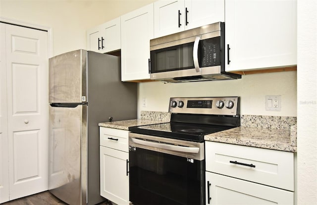 kitchen featuring stainless steel appliances, white cabinetry, dark hardwood / wood-style floors, and light stone counters