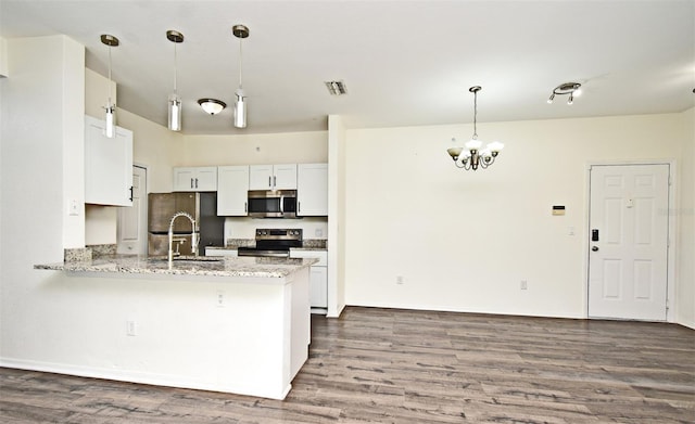 kitchen featuring kitchen peninsula, white cabinets, hanging light fixtures, and appliances with stainless steel finishes