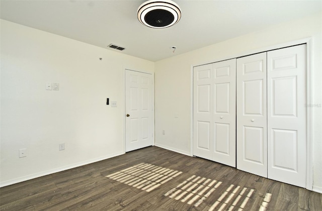 unfurnished bedroom with dark hardwood / wood-style floors and a closet