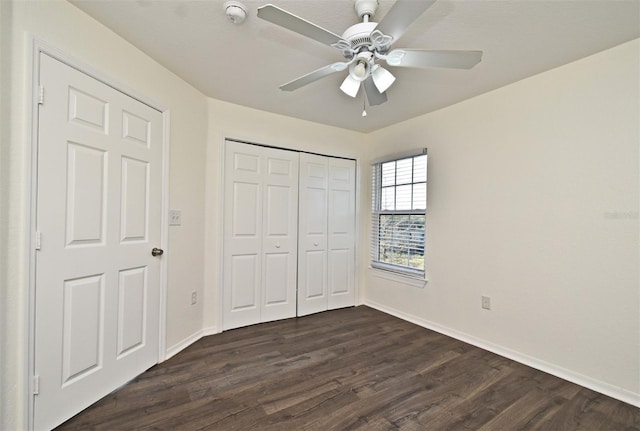 unfurnished bedroom with ceiling fan, dark hardwood / wood-style flooring, and a closet