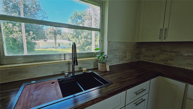 kitchen with a healthy amount of sunlight, wooden counters, and tasteful backsplash