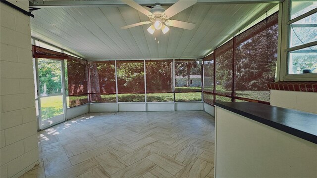 unfurnished sunroom with ceiling fan, plenty of natural light, and wooden ceiling