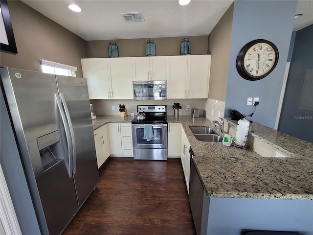 kitchen featuring appliances with stainless steel finishes, light stone countertops, a peninsula, and a sink