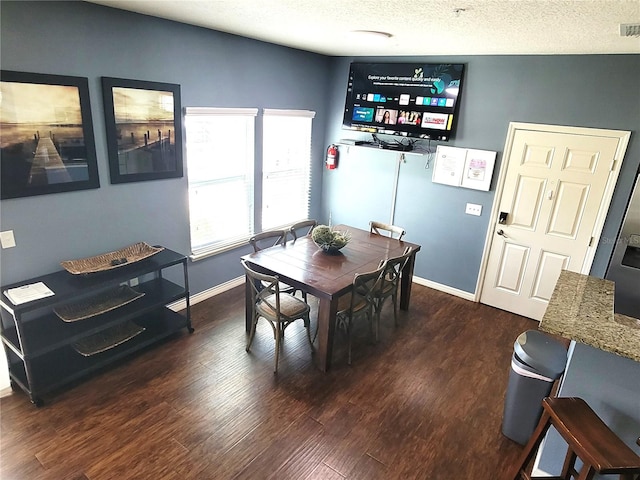 dining space with dark hardwood / wood-style flooring and a textured ceiling