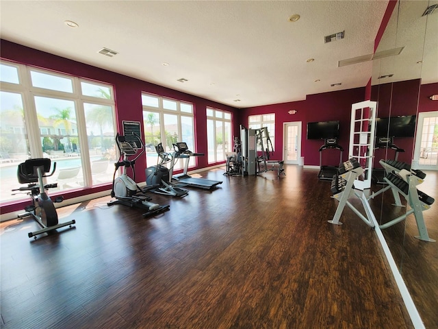 gym featuring a textured ceiling, a healthy amount of sunlight, and hardwood / wood-style floors