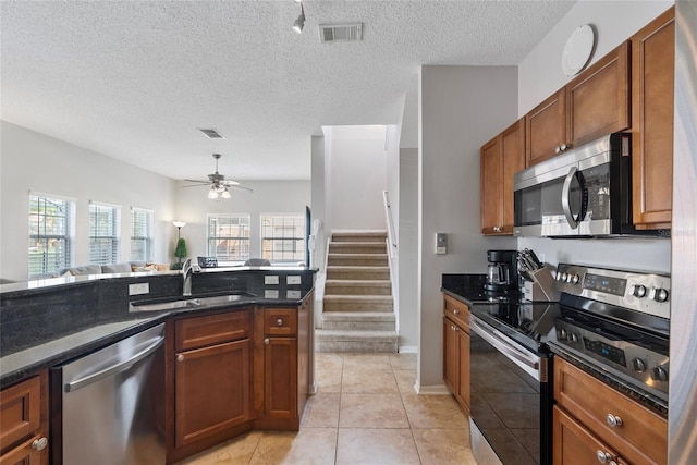 kitchen featuring appliances with stainless steel finishes, a textured ceiling, ceiling fan, sink, and light tile patterned floors