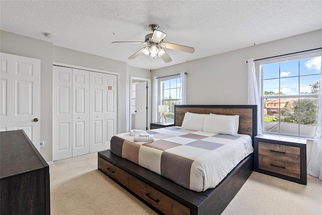 carpeted bedroom with ceiling fan, a textured ceiling, and a closet