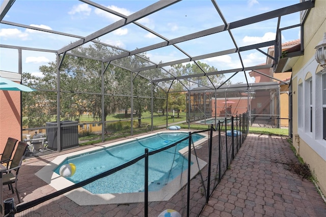 view of pool featuring glass enclosure, cooling unit, and a patio area